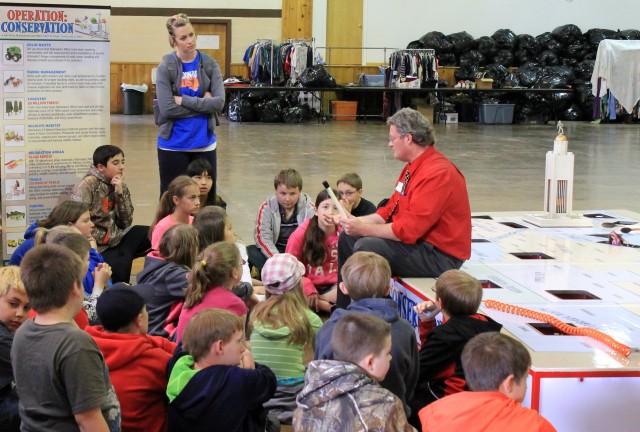 Scott Snell (seated at right), public relations specialist with the Upper Big Blue NRD, visits with 5th grade students on Tuesday during the 11th annual Conservation Festival about Conservation Practices and Natural Resources Districts While explaining an educational interactive game he designed called “Operation: Conservation”